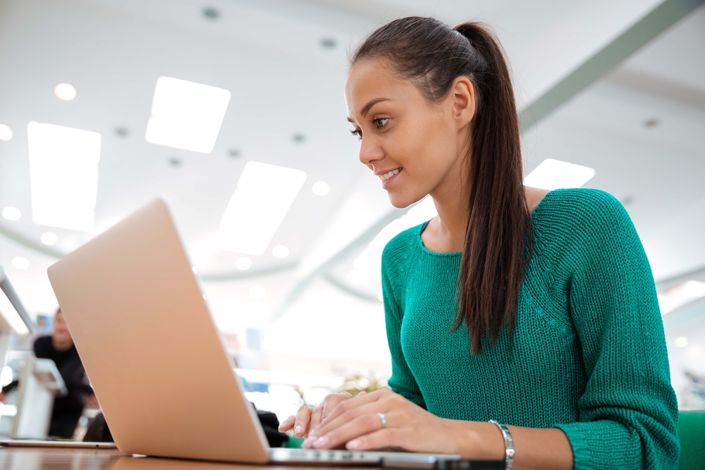 Estudante sorrindo enquanto utiliza um notebook